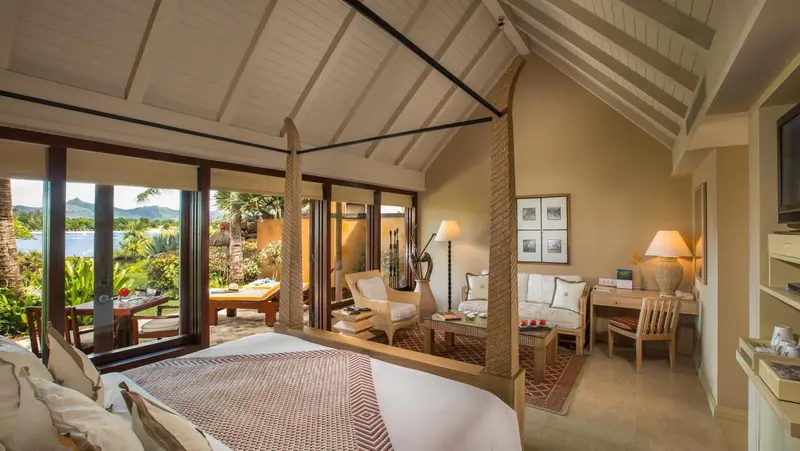 Une chambre lumineuse s'ouvre sur une terrasse avec vue sur la végétation.