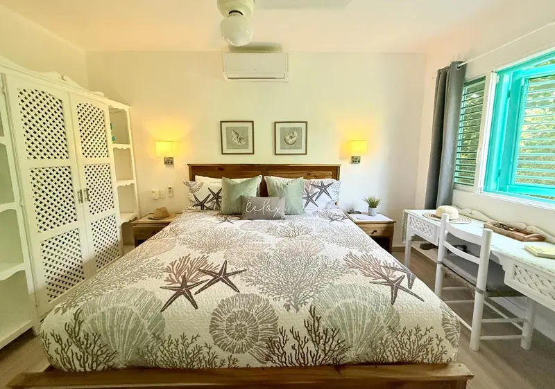 Une chambre lumineuse avec un grand lit décoré de motifs marins.