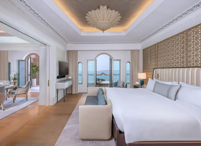 Chambre lumineuse avec un grand lit et une vue sur la mer.