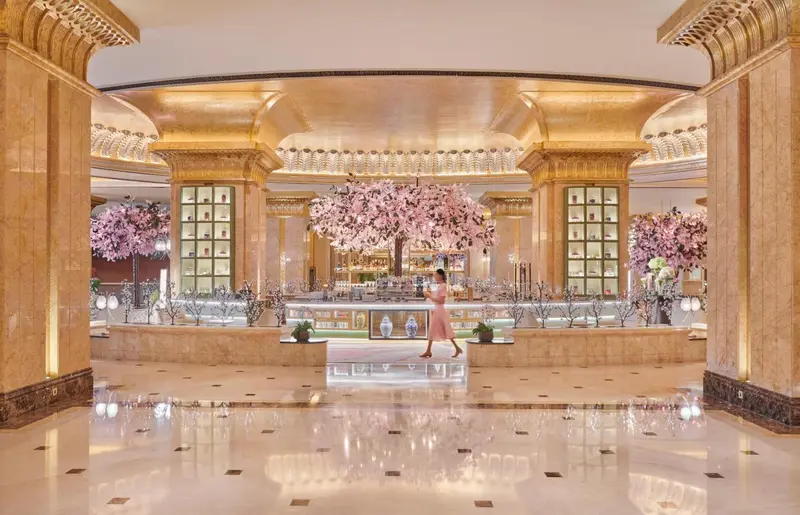 Vaste hall d'accueil aux colonnes de marbre et aux arrangements floraux.