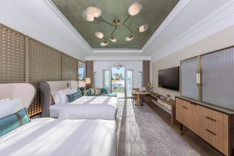 Chambre lumineuse avec deux lits et un éclairage moderne au plafond.