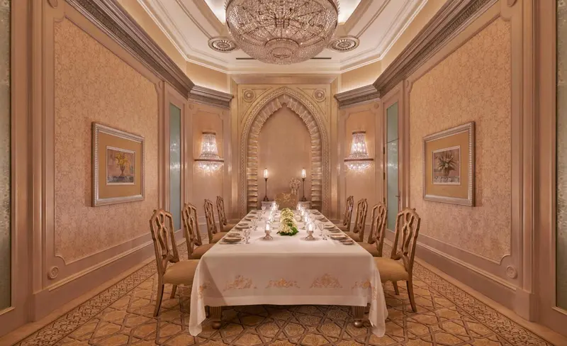 Une longue table est dressée dans une salle à manger élégante.