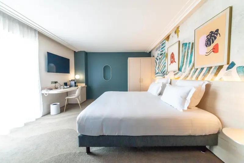 Une chambre lumineuse avec un grand lit et un bureau.