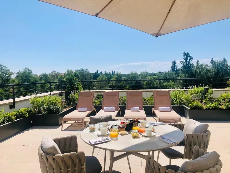 Terrasse aménagée avec chaises longues et table pour le petit-déjeuner.