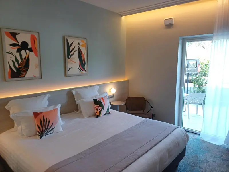 Une chambre lumineuse avec un grand lit et un accès à une terrasse.
