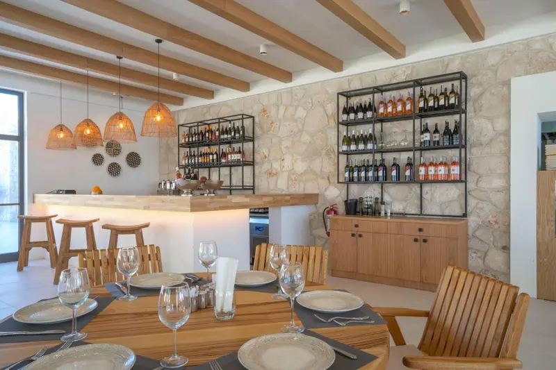 Une table est dressée dans une salle lumineuse avec un comptoir et des étagères à vin.