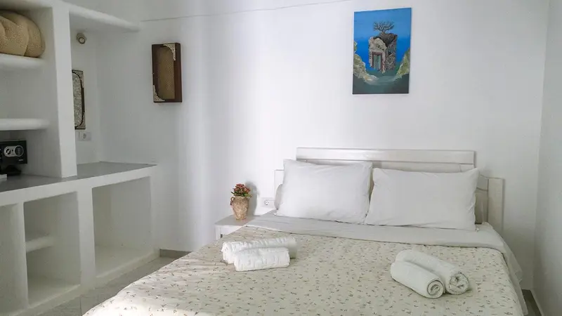 Une chambre lumineuse avec un lit blanc et des éléments décoratifs muraux.