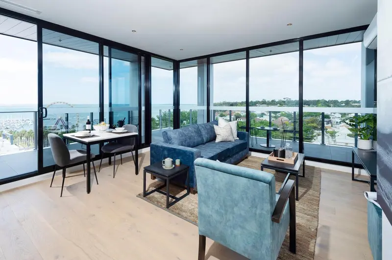 Un salon lumineux avec coin repas offre une vue sur la mer et la ville.