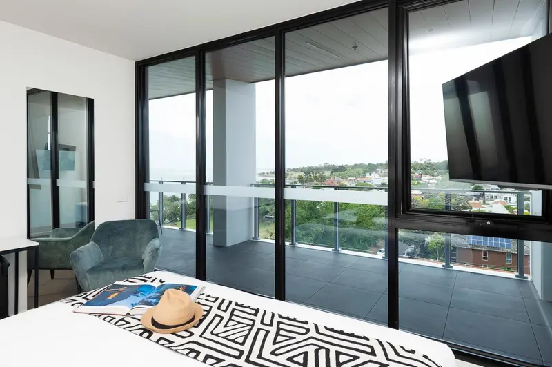 Une chambre moderne avec un grand balcon donnant sur une vue urbaine.