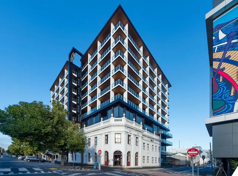 Façade moderne d'un bâtiment avec des balcons et une partie ancienne en pierre.
