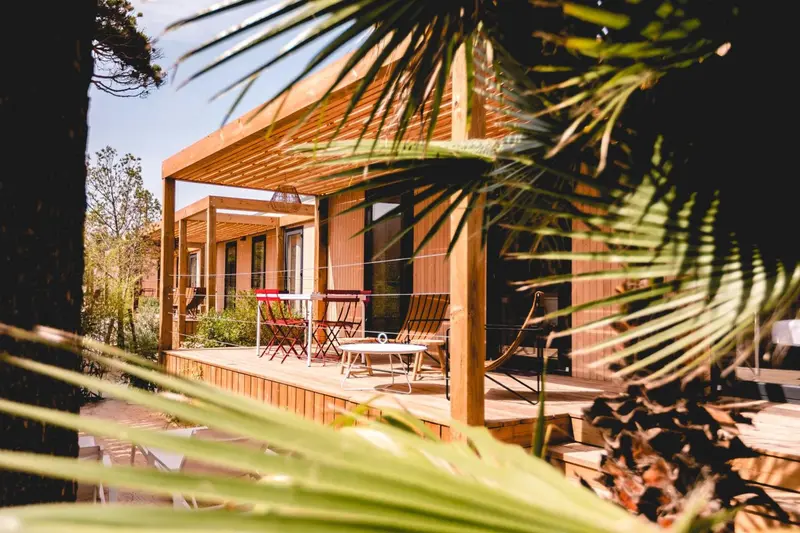 Terrasse en bois avec mobilier de jardin et bâtiments en arrière-plan.