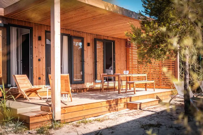 Terrasse en bois avec mobilier de jardin devant un logement.
