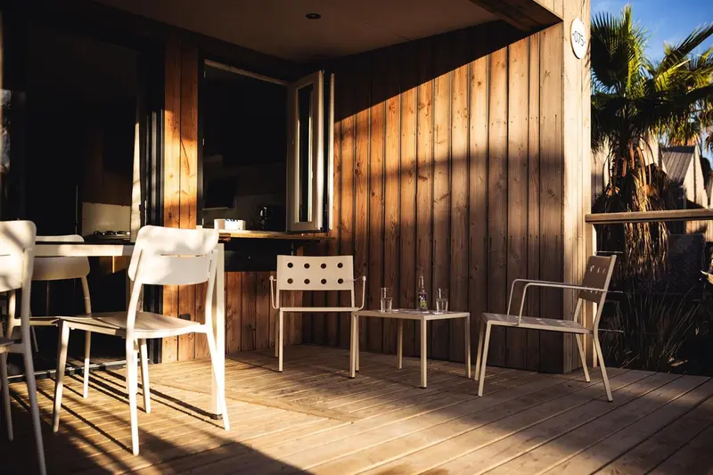 Terrasse en bois avec mobilier blanc et table.
