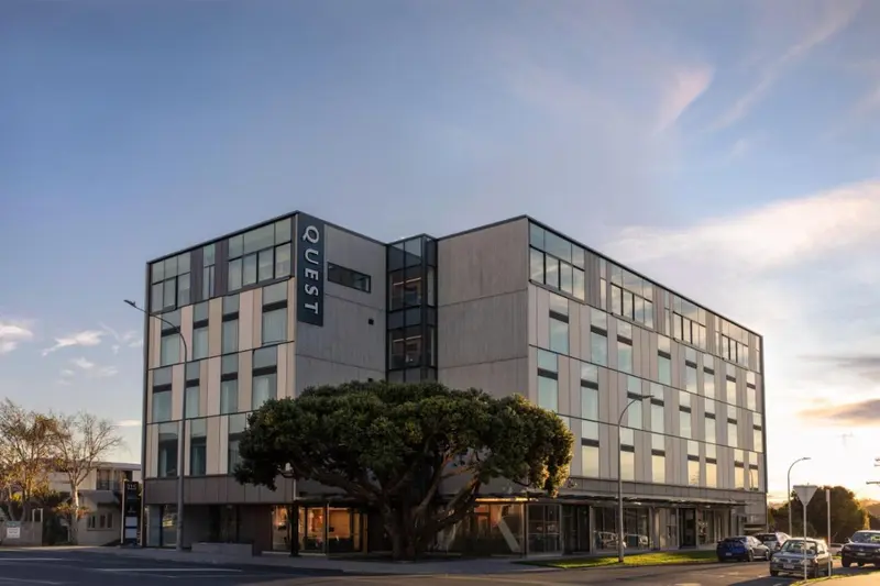 Façade moderne d'un bâtiment à plusieurs étages avec des fenêtres rectangulaires et un nom vertical.