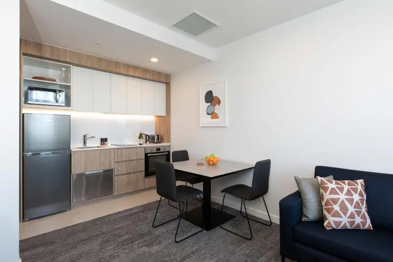 Une cuisine moderne s'ouvre sur un coin repas avec une table et des chaises.