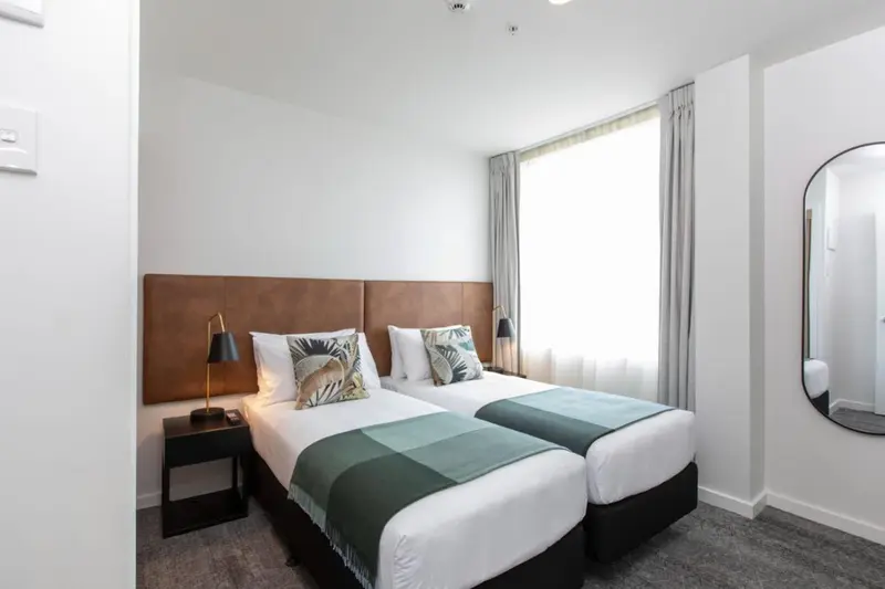 Une chambre lumineuse avec deux lits simples et une décoration sobre.