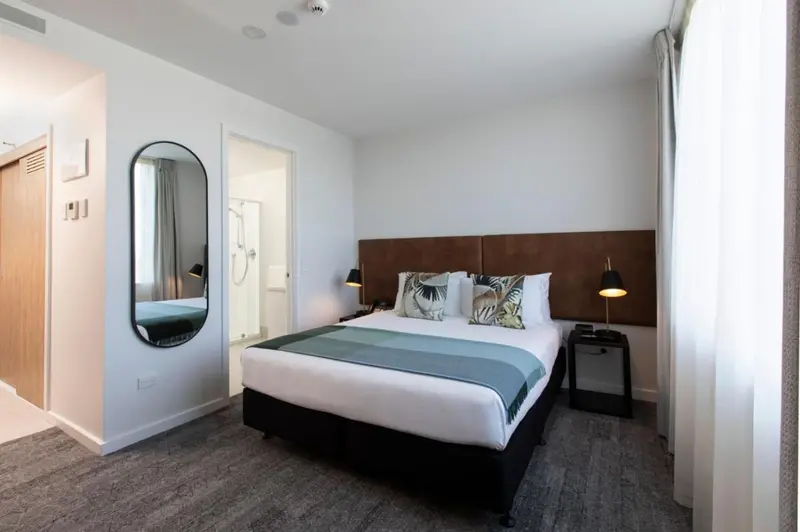 Une chambre lumineuse avec un grand lit et un miroir ovale.