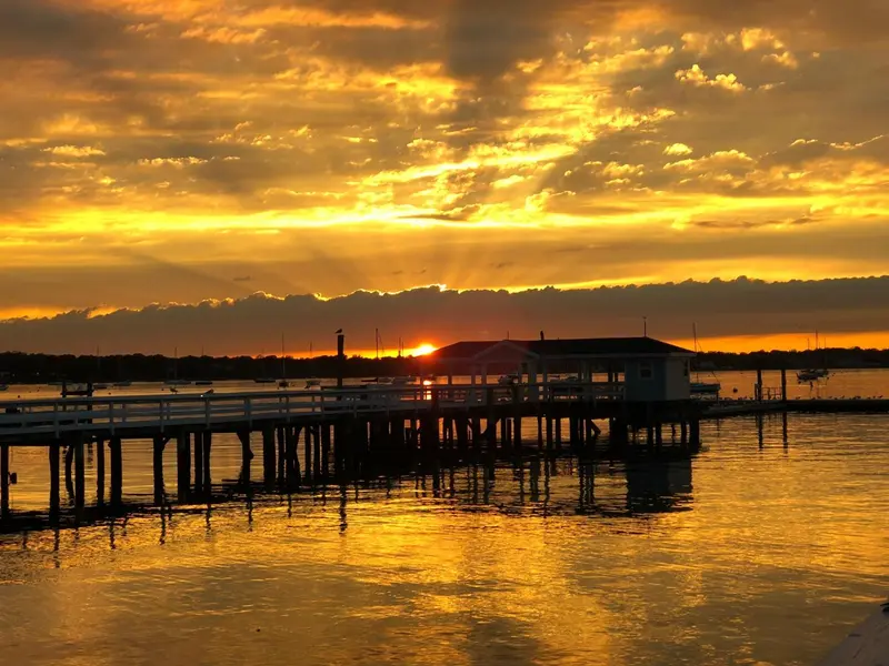 Un ponton s'avance sur l'eau au coucher du soleil.