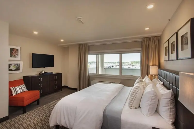 Une chambre d'hôtel lumineuse avec un grand lit et une vue sur un port.