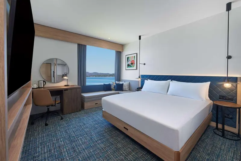 Chambre lumineuse avec un grand lit et une vue sur la mer.