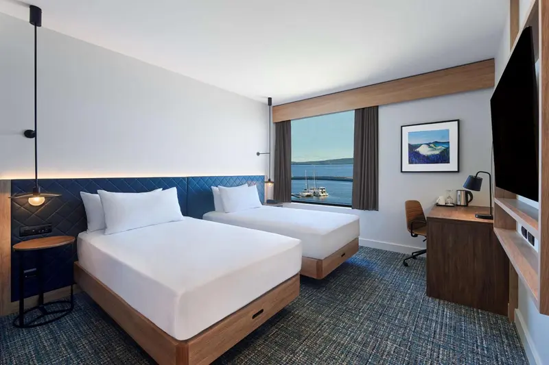 Chambre moderne avec deux lits simples et vue sur la mer.