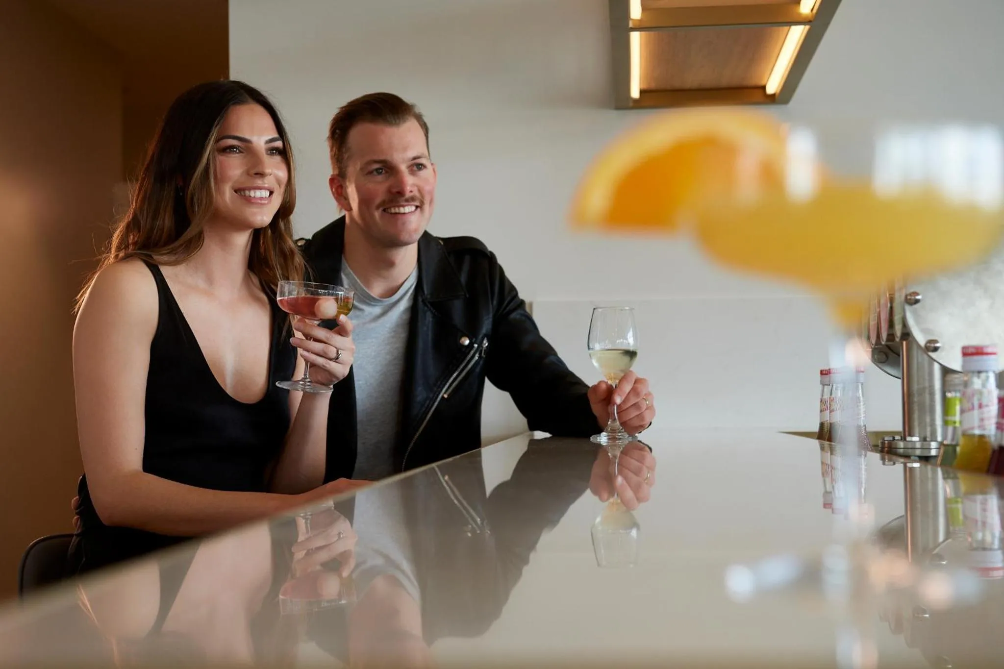 Un couple souriant déguste des boissons au comptoir d'un bar.
