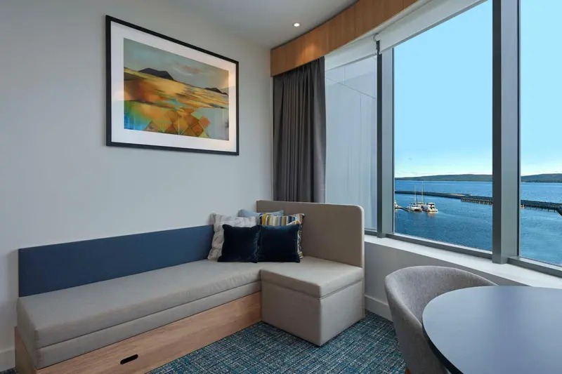 Espace de détente lumineux avec canapé intégré et vue sur la mer.
