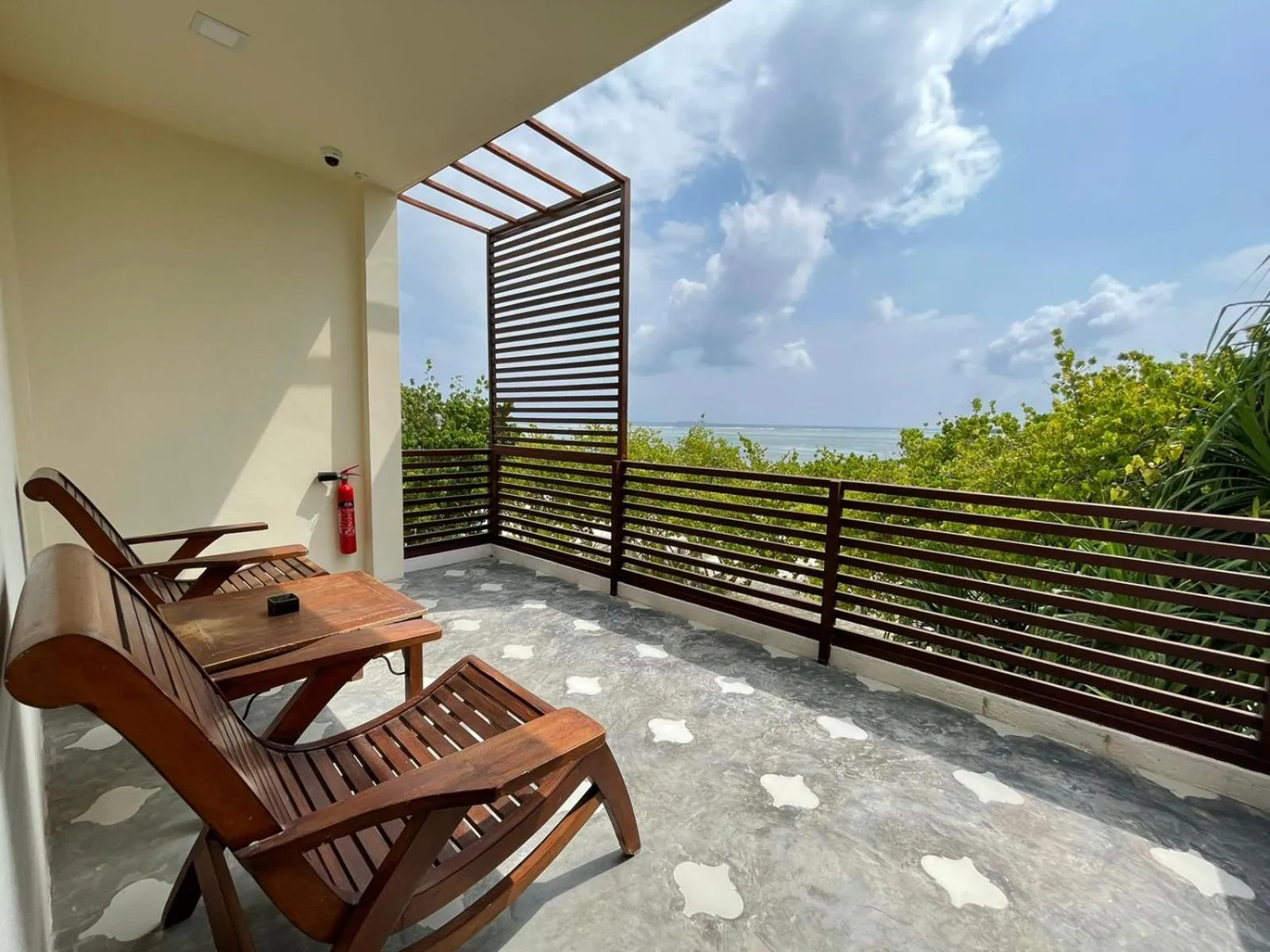Deux fauteuils en bois sur une terrasse avec vue sur la mer et la végétation.