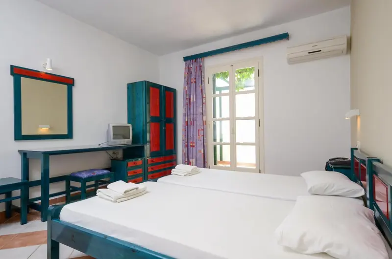 Une chambre lumineuse avec deux lits simples et un bureau.