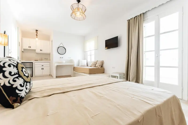 Une chambre lumineuse avec un lit et une kitchenette.
