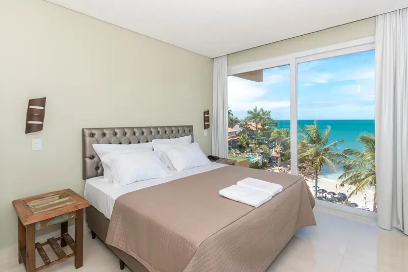 Une chambre lumineuse avec un grand lit face à une vue sur la mer.