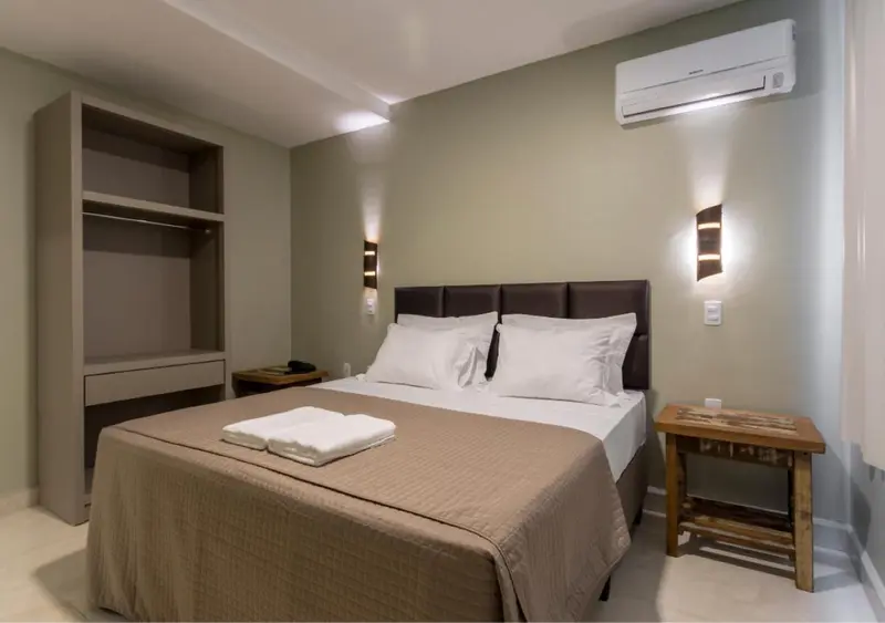 Une chambre avec un grand lit recouvert d'une couverture et de coussins blancs.