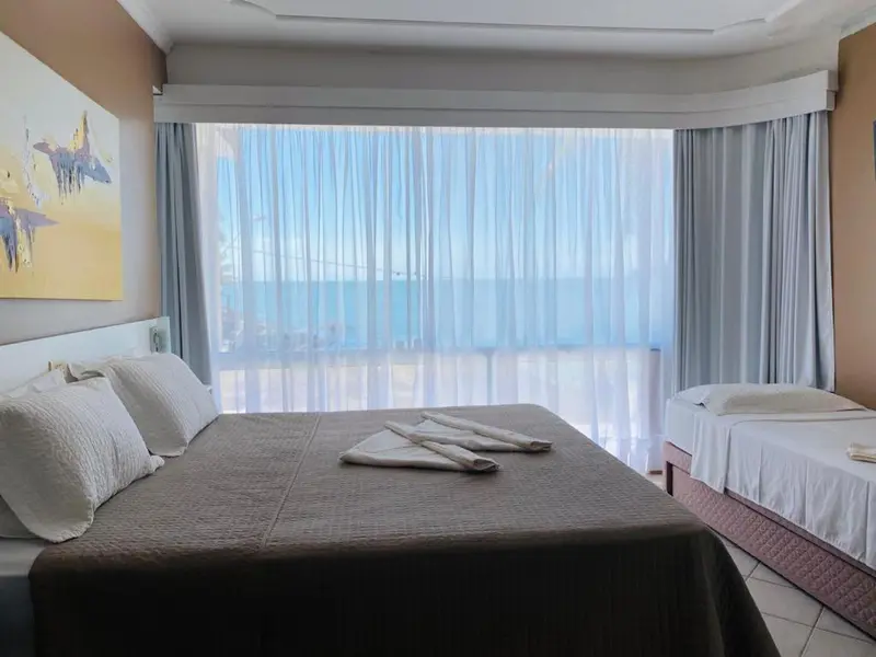 Chambre avec un grand lit et vue sur la mer à travers de larges baies vitrées.