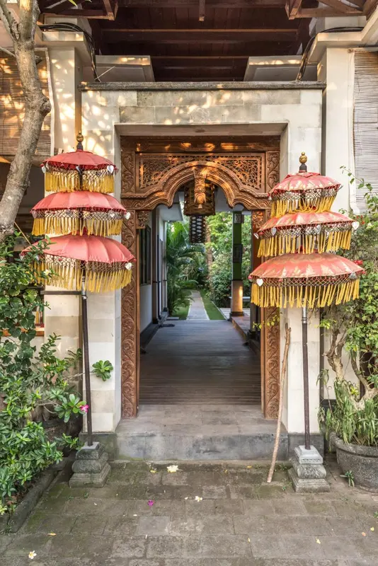 Entree ornee de parasols traditionnels menant a une allée ombragée.