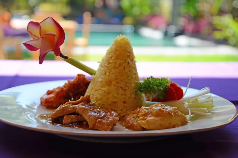 Assiette de riz et de viande décorée d'une fleur et de légumes.