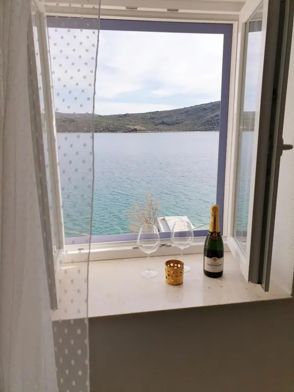 Vue sur la mer depuis une fenêtre avec une bouteille et des verres.