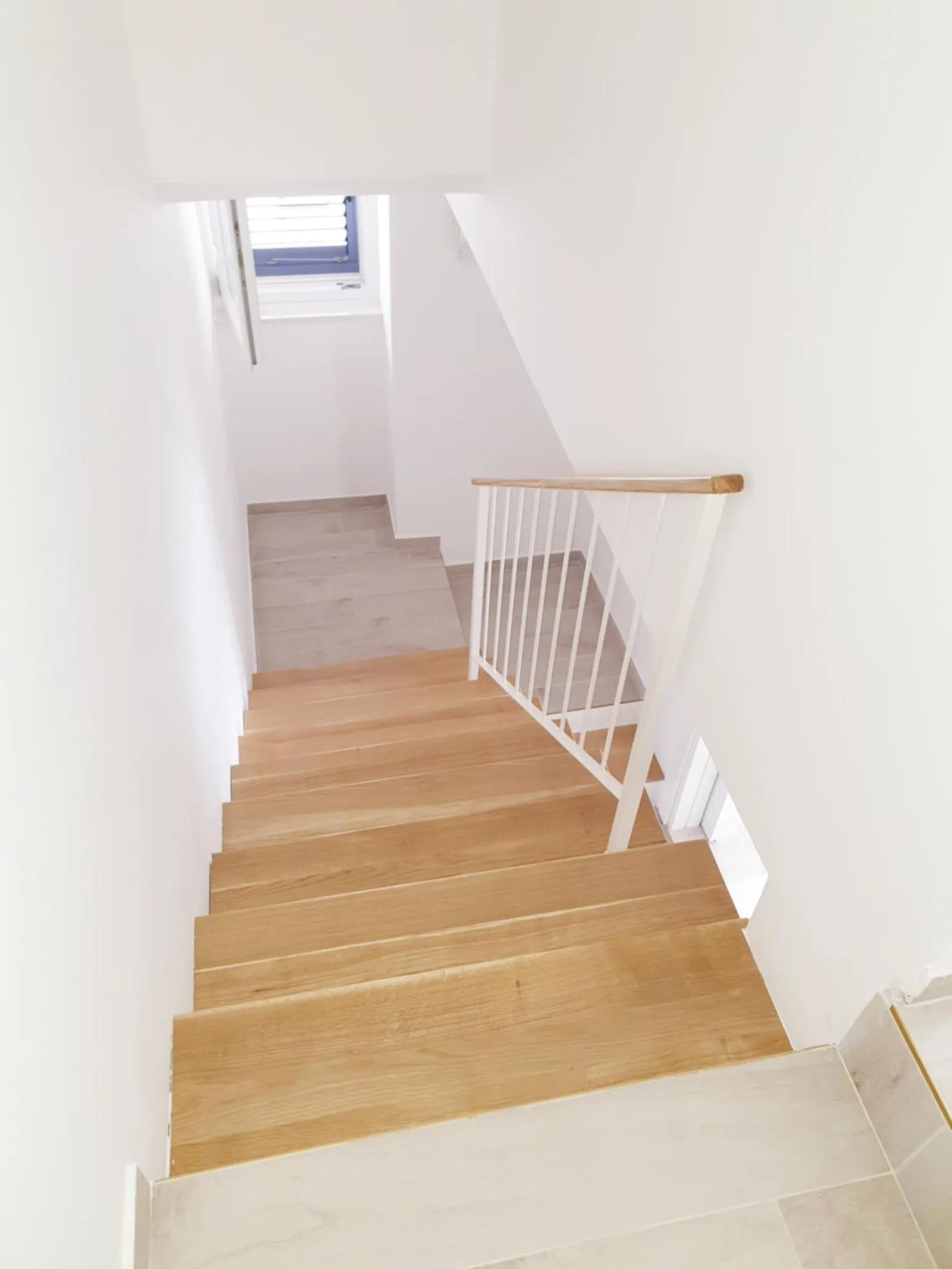 Escalier en bois clair dans un intérieur lumineux.