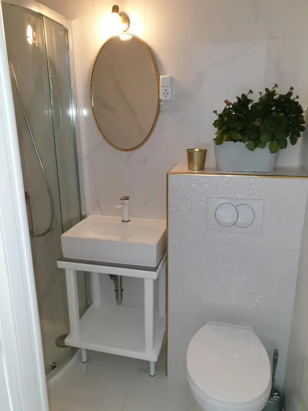 Une salle de bain claire avec douche, lavabo et toilettes.