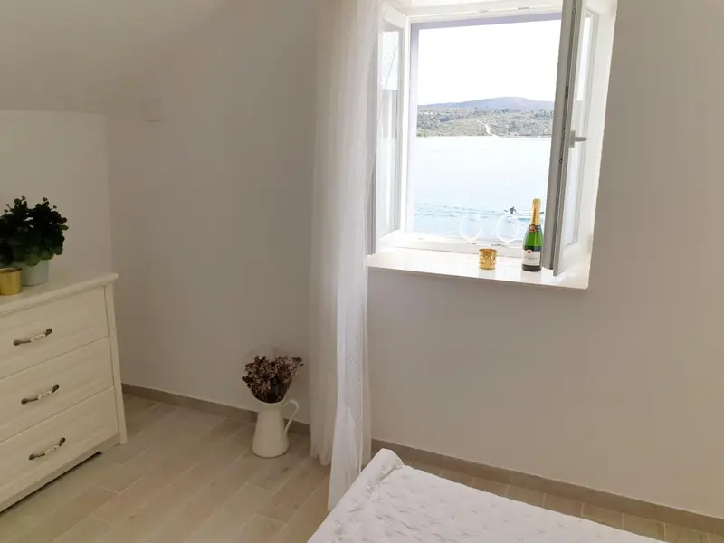 Une chambre lumineuse avec vue sur la mer par une fenêtre.