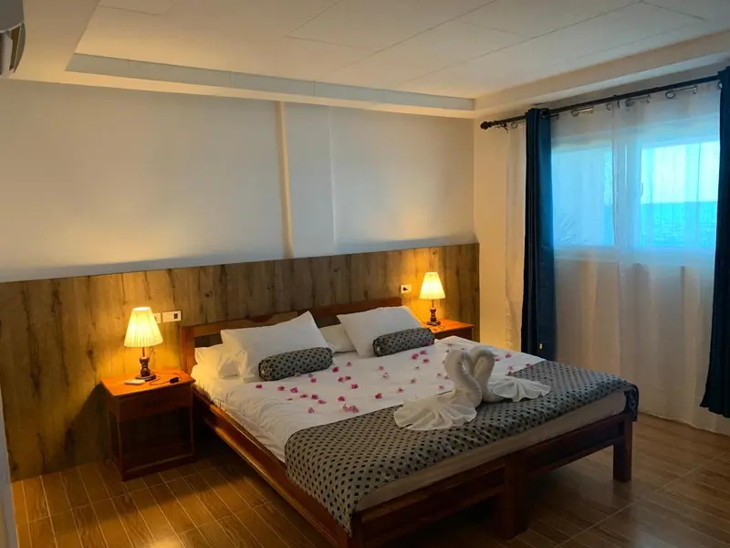 Une chambre lumineuse avec un grand lit décoré de pétales et de serviettes en forme de cygnes.