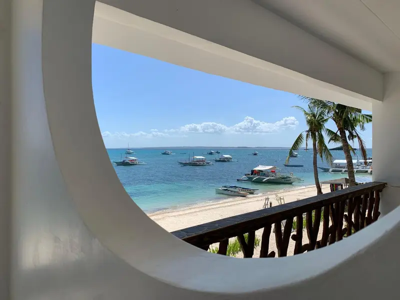 Vue sur une plage et des bateaux amarrés dans une eau turquoise.