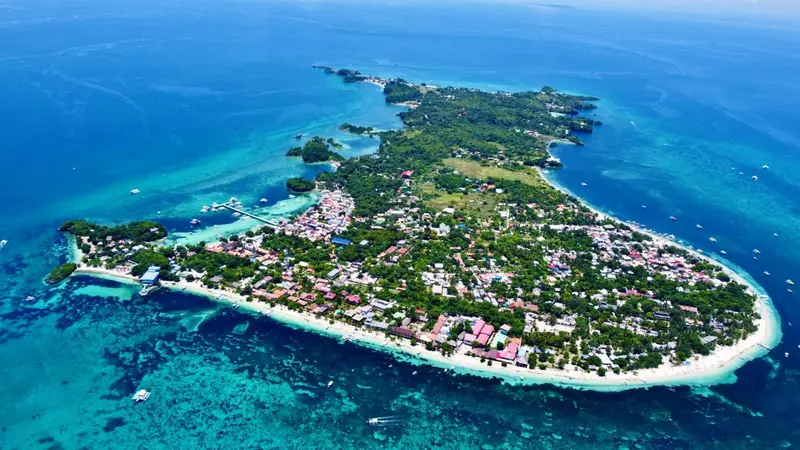 Vue aérienne d'une île tropicale bordée de plages et de végétation luxuriante.