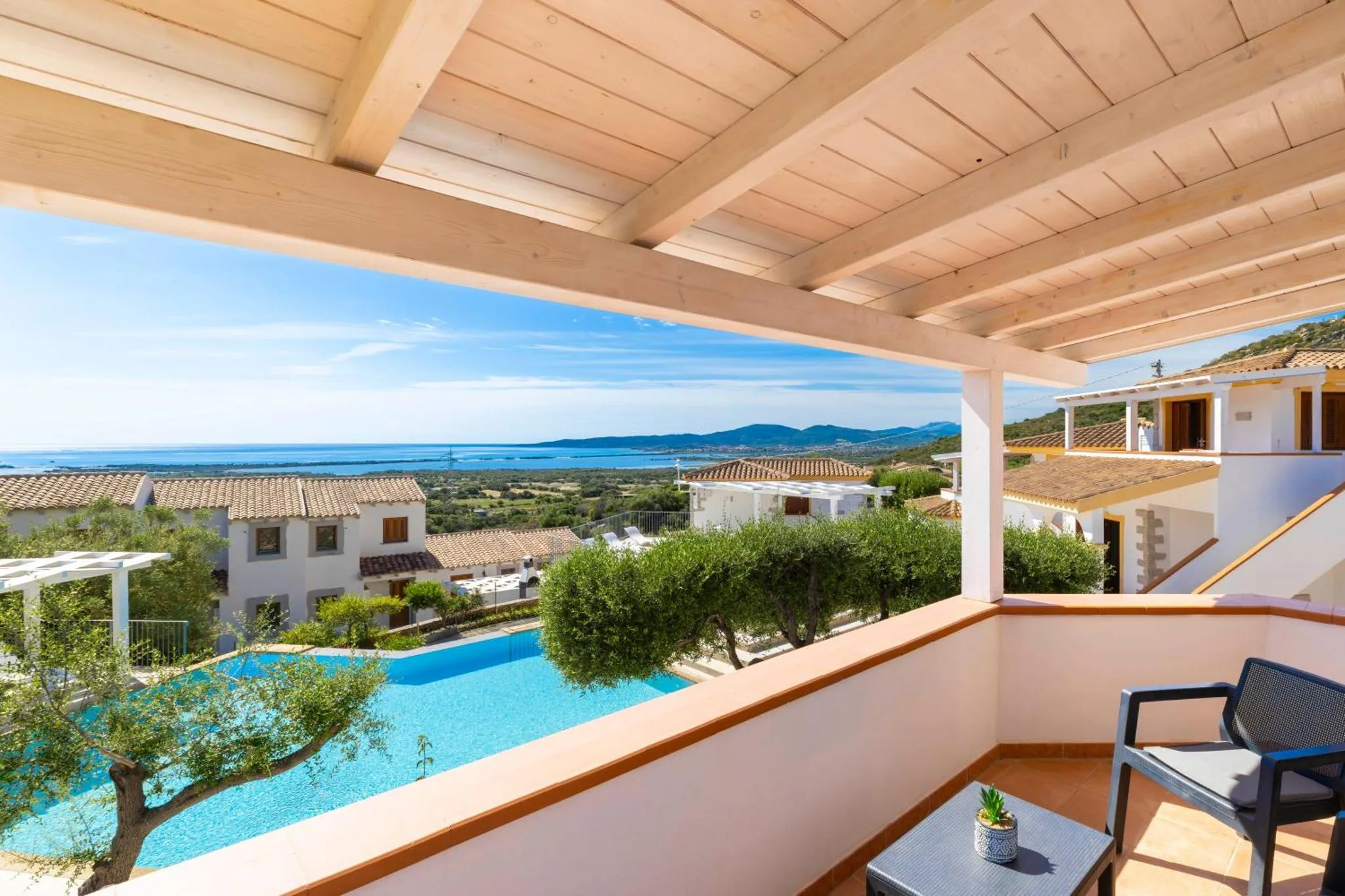 Vue sur la mer et la piscine depuis une terrasse ombragée.