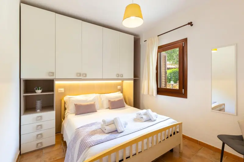 Une chambre lumineuse avec un lit double et des rangements.