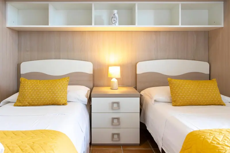 Deux lits simples avec des oreillers jaunes dans une chambre lumineuse.