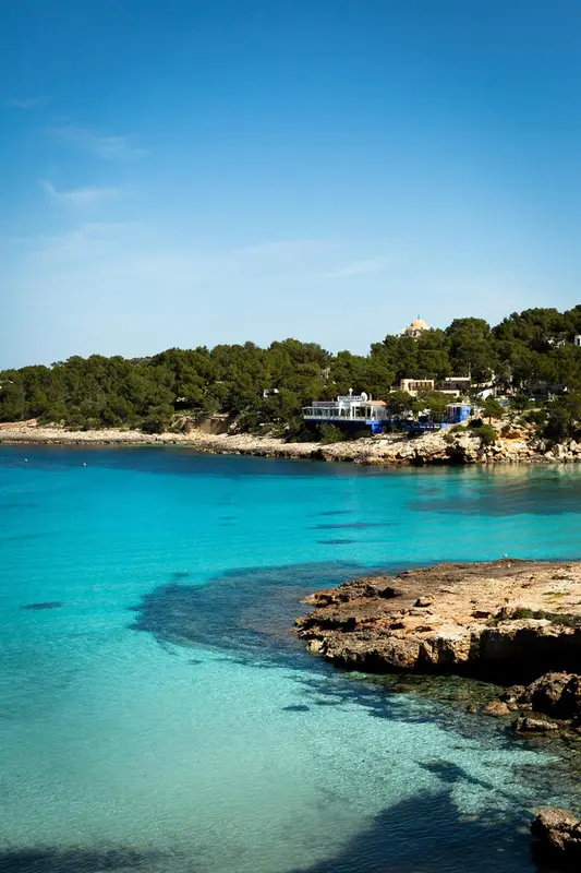 Une plage de sable clair borde une eau turquoise sous un ciel bleu.