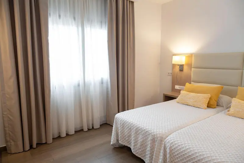 Une chambre lumineuse avec deux lits simples et des oreillers jaunes.