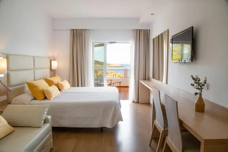 Une chambre lumineuse avec un grand lit et une vue sur la mer.