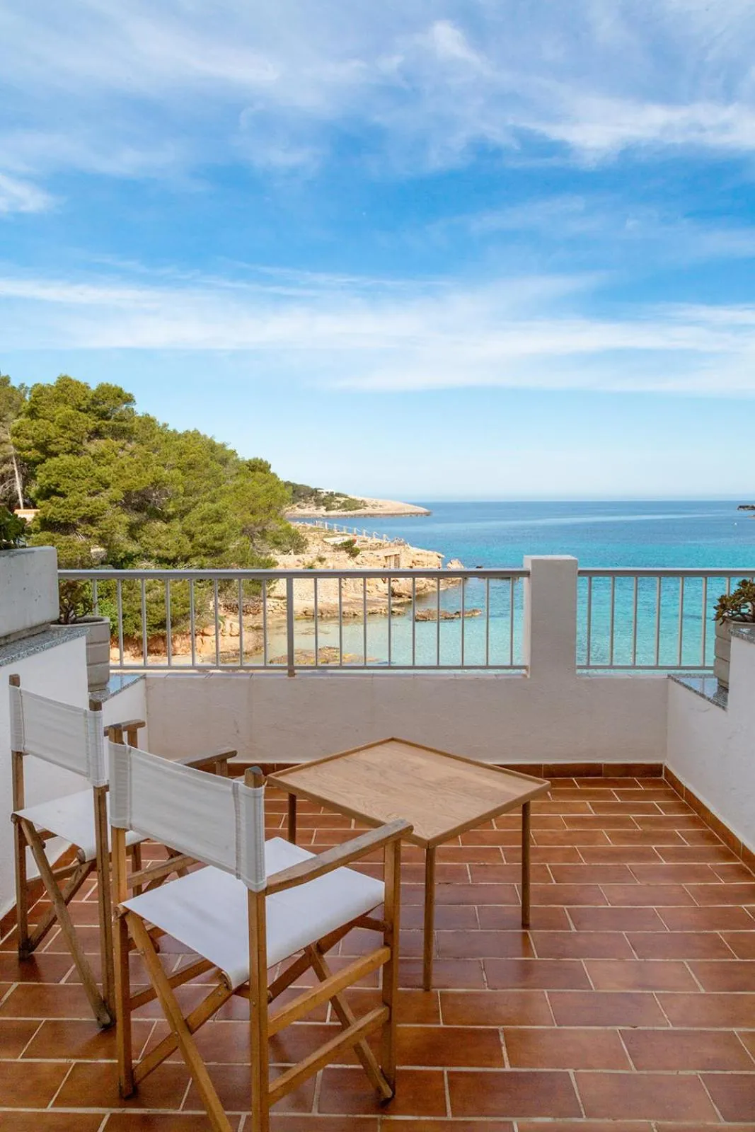 Terrasse carrelée avec mobilier en bois donnant sur la mer.