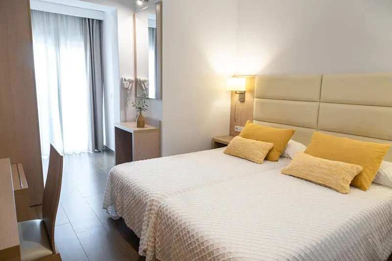 Une chambre lumineuse avec un grand lit et des coussins décoratifs.